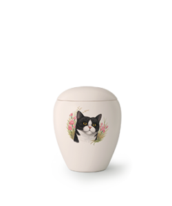 Eine cremefarbene Urne mit einem gemalten Bild einer schwarz-weißen Katze, umgeben von rosa Blumen auf der Vorderseite. Aurora Tierkrematorium